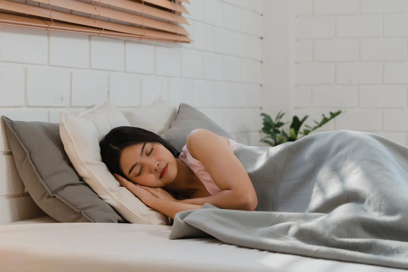 Woman sleeping soundly on her side in a bright bedroom